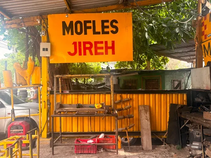 Rótulo amarillo Mofles Jireh en la entrada del taller
